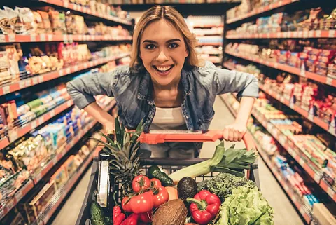 chica sonriente empuja carro de la compra